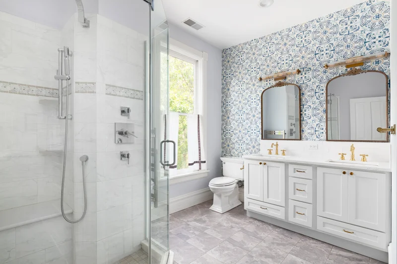 Bright bathroom remodel featuring blue patterned wallpaper and white vanity. Bright bathroom remodel featuring blue patterned wallpaper and white vanity.