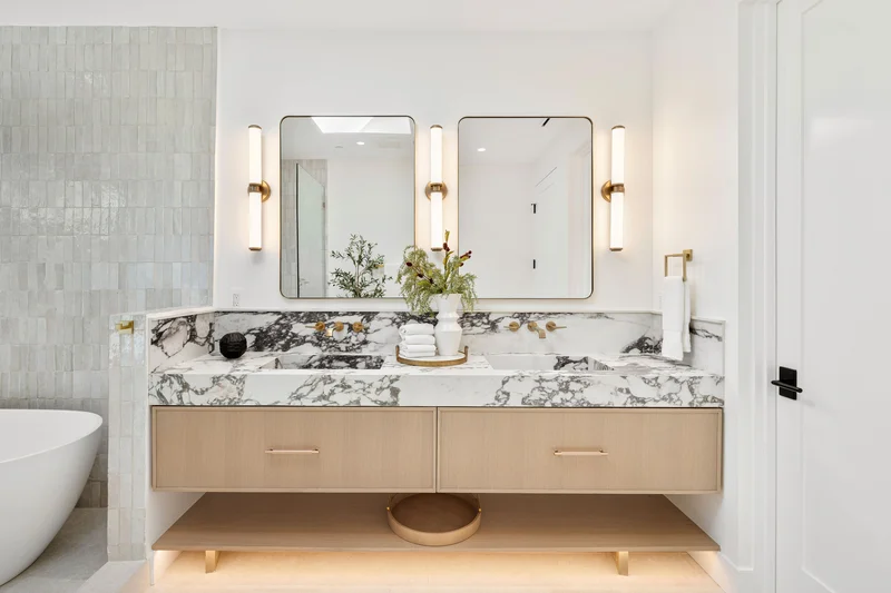 Luxury bathroom remodel with a marble double vanity and modern light wood cabinets. Luxury bathroom remodel with a marble double vanity and modern light wood cabinets.